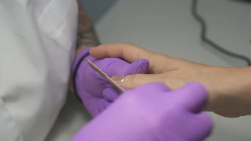 Manicurist Filing Client's Nails in Salon