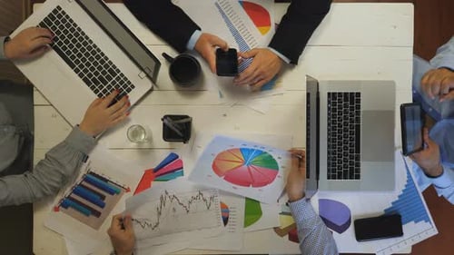Top View to Male and Female Arms of Coworkers Plan a Future Project Sitting at Table Group of