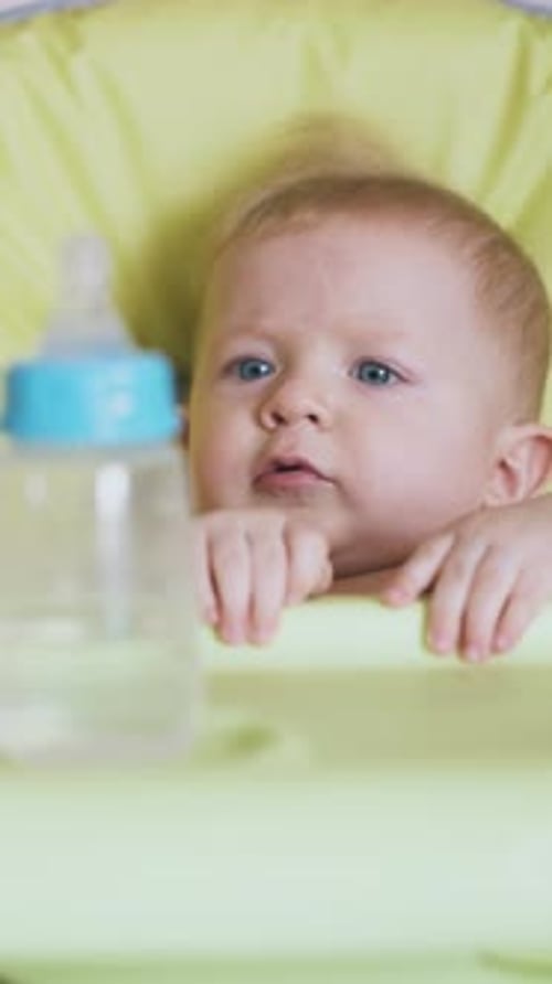Niña le da una botella de agua a un niño sentado en una silla alta