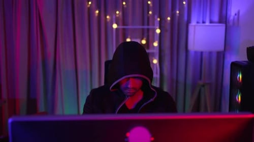 Hooded Person Working at Computer at Night