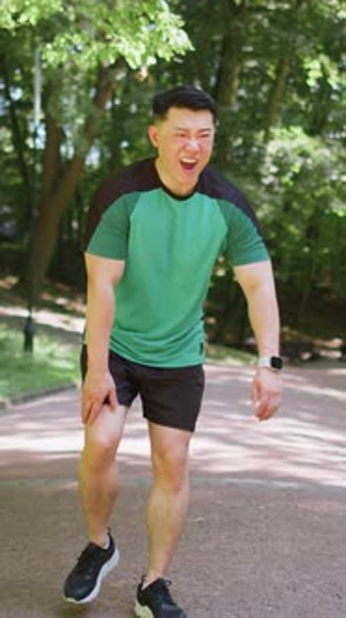 Chinese Runner Sportsman with Muscle Knee Pain in Park Trauma Injury While Jogging Leg Muscle Cramp