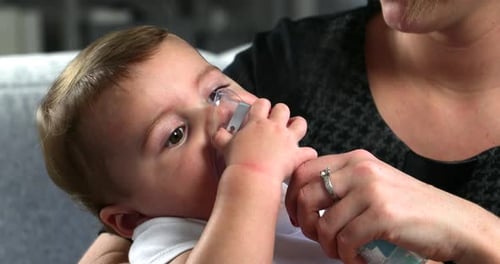 Infant Receives Nebulizer Treatment Held by Mother