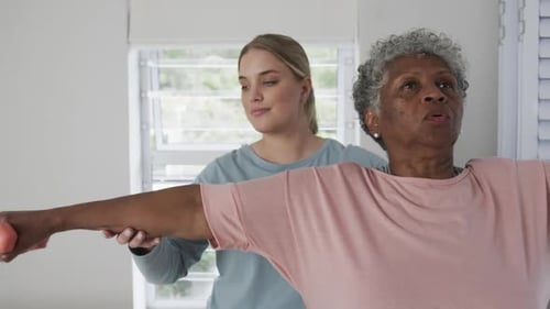Woman Assists Senior with Light Dumbbell Exercise