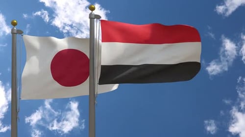 Japan and Yemen Flags Waving Against Blue Sky