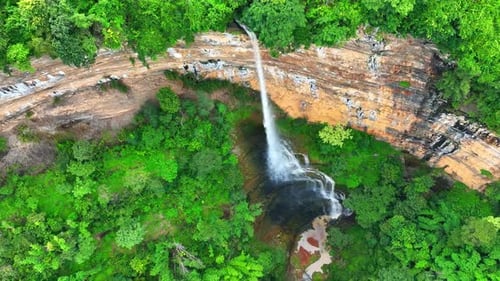 Drone captures majestic waterfall cascading from cliff.