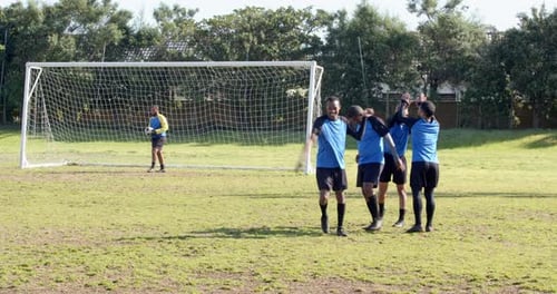 Jugadores de fútbol que salen del campo después del partido cerca del poste de la portería en un día soleado