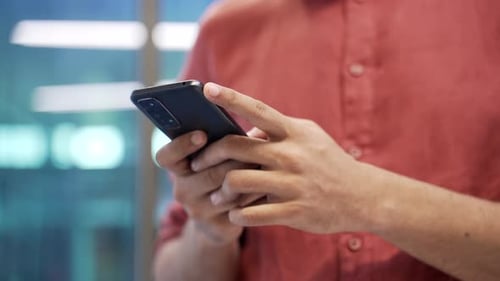 Gros plan des mains masculines tenant un téléphone portable. L'homme d'affaires utilise un smartphone en position debout