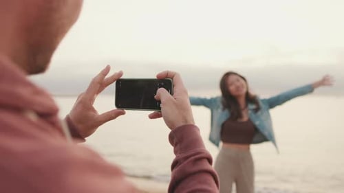 Man takes photo of woman on the shore