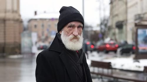 A Bearded Man in a Black Hat Stands on a Busy City Street