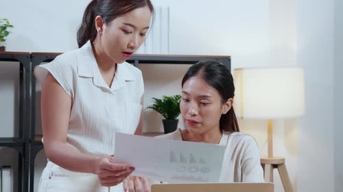 Two Women Collaborating on Data Review in Office