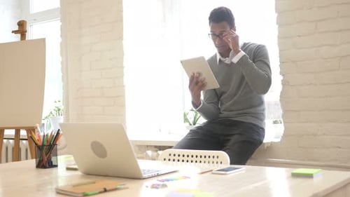 Young Adult Uses Tablet on Windowsill