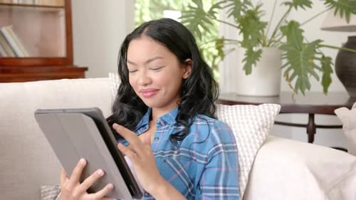 Young Woman Using Tablet on Sofa at Home
