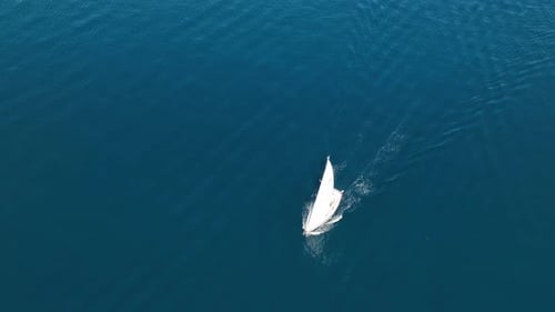 An aerial view of the sail yacht on the blue sea. Transparent clear water in the sea.