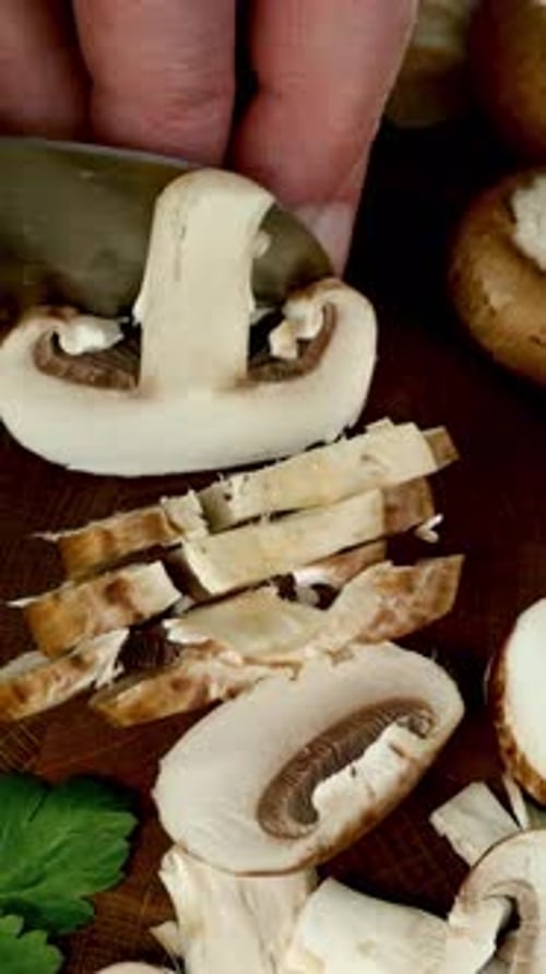 Rohe Champignon-Pilze, mit einem Messer auf einem Schneidebrett in Scheiben geschnitten