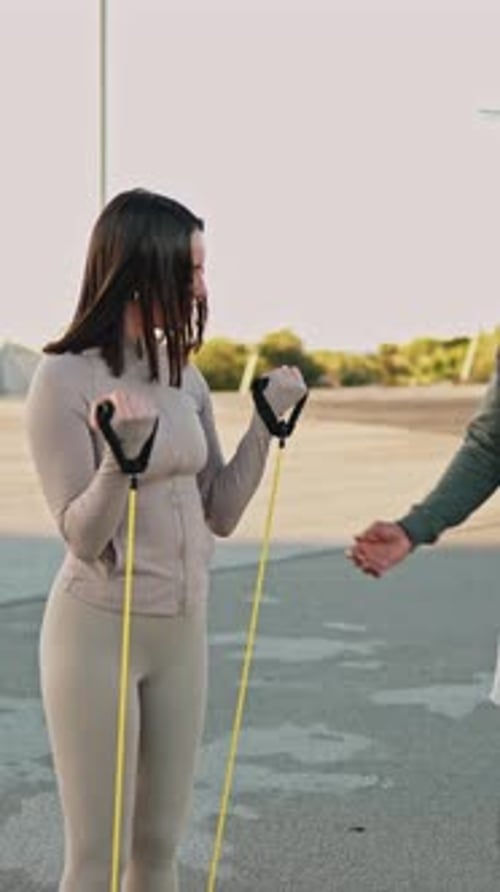 Femme faisant des flexions des biceps avec bande de résistance avec un entraîneur personnel