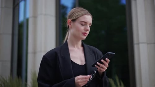 Woman Stands Outside Building Using Phone