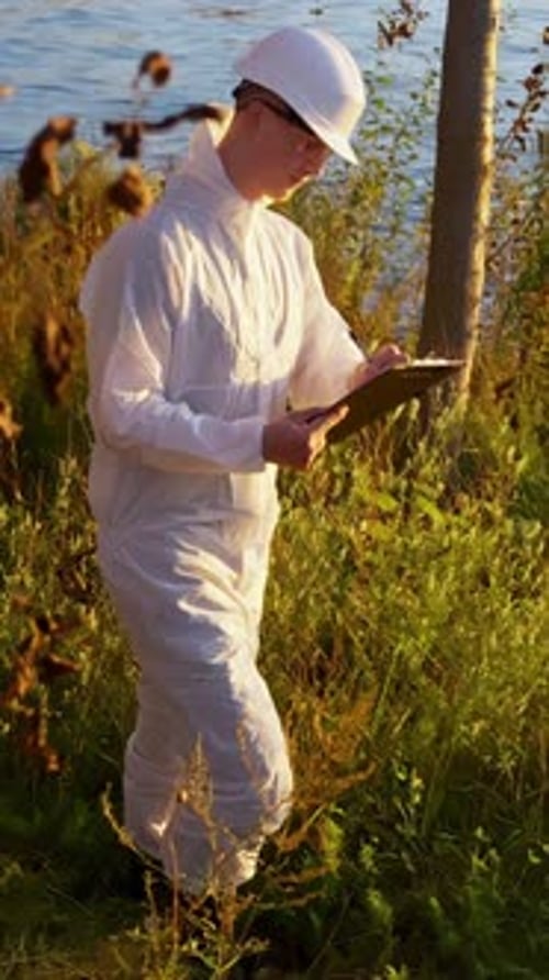 Scientist in white suit writing on a clipboard