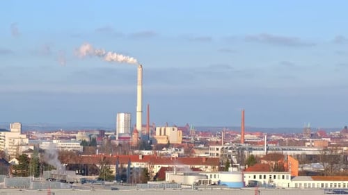 Skyline of industrial part of a city with chimney of power plant producing smoke