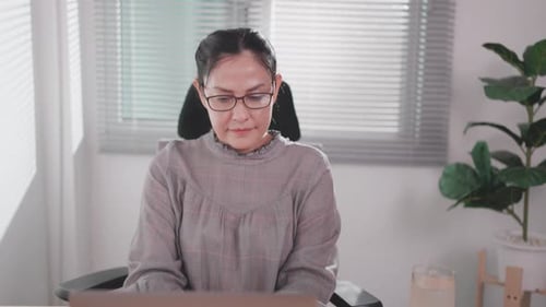 Asian woman typing on laptop keyboard sitting at office in online workspace with modern technology