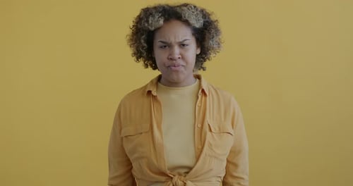 Woman Expressing Anger and Frustration on Yellow Background