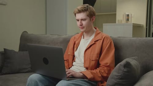 Hombre de 20 años lee malas noticias usando una computadora portátil Un hombre blanco molesto está nervioso por algo mirando la computadora