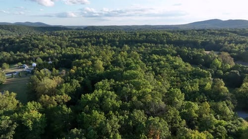 Houses between dense green lush forest landscape in countryside of USA. Aerial wide shot. Suburb