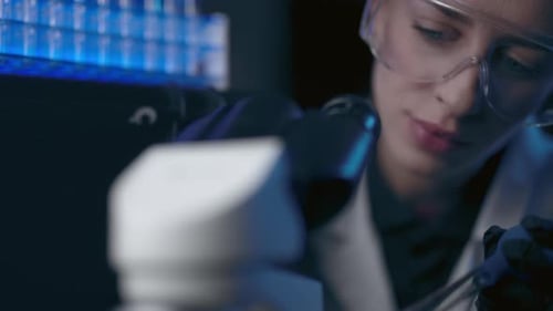 Woman analyzing sample with microscope in laboratory setting