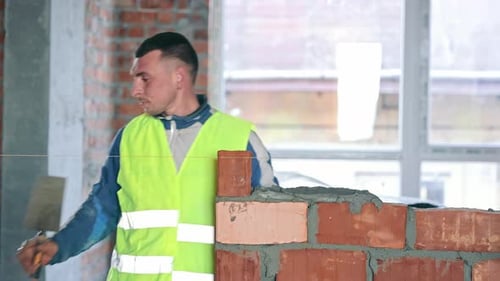 Construction Worker Building Brick Wall A Construction Worker in a Highvisibility Vest Carefully