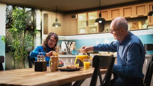 Senior Couple Toasting with Juice at Breakfast Table