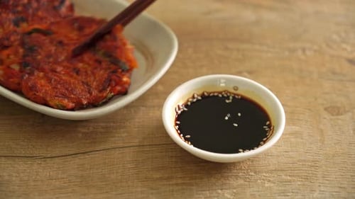 Dipping Pancake in Sauce with Chopsticks on Table