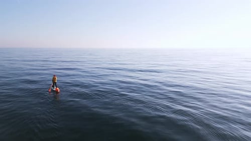 Man Floats on SUP Board on the Clear Azure Calm Waters of the Black Sea Aerial View