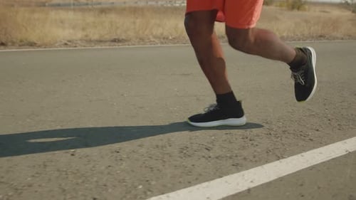 Male Legs in Sports Shoes Run Along the Road