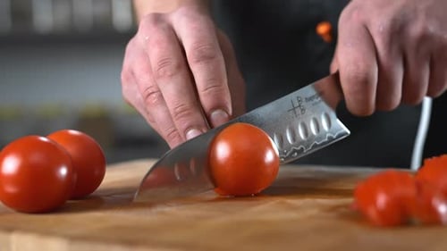 Chef slicing tomatoes with a high quality knife,wooden board,vegetable.