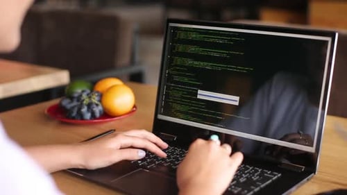 Back View Over the Shoulder Shot of Developer Programmer Female with Laptop Program Code and Script