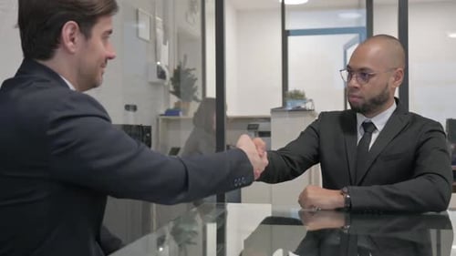 Businessmen Shaking Hands at Conference Table