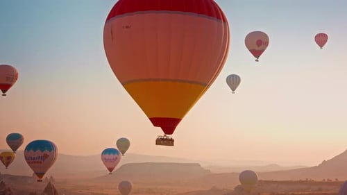 Hot Air Balloons Flying at Sunrise Over Mountains