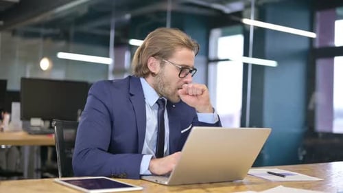 Man in Suit Works on Laptop in Office