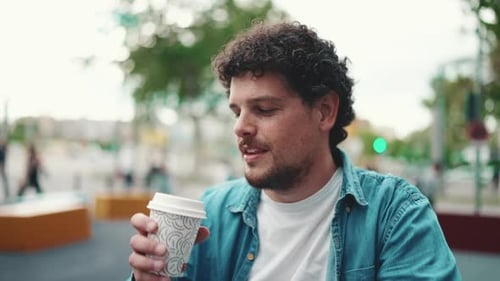 Close-up of man sitting and drinking coffee on busy street modern city background