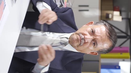 Adult Wearing Suit Points at Papers Indoors