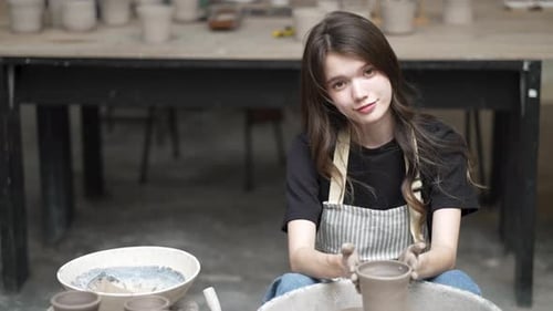 Young women is making earthenware at workshop.