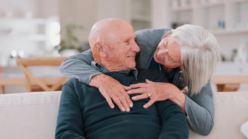 Senior Couple Embracing Affectionately on Cream Couch