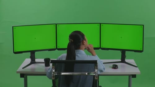 Back View Of Asian Woman Thinking While Working With Mock Up Multiple Monitor In Green Screen