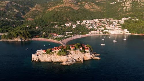 Flying around the island of Sveti Stefan at sunset showing the houses and luxury resort in the adria