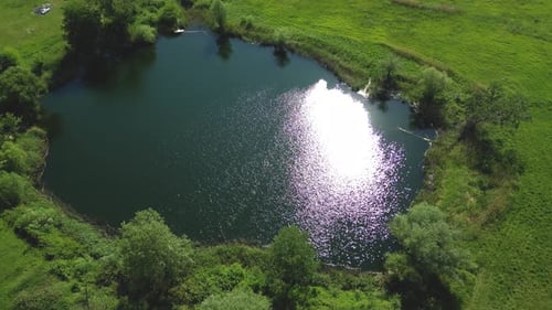 Top view aerial flight over small lake of perfectly round shape. Moving up, clear turquoise water of