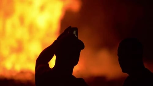 A huge celebration bonfire in Belfast. Bonfire collapses. People watch on and celebrate by dancing a