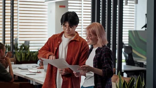 Two Friendly Colleagues Talk Together While Discussing New Contract Standing in the Modern Office