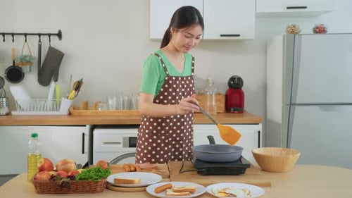 Young Woman Cooking Tasty Breakfast in Bright Kitchen