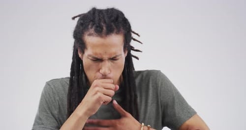 A handsome young man coughing against a grey background