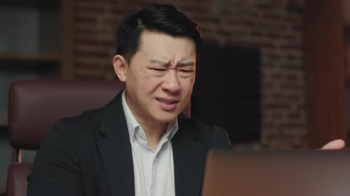 Frustrated Man Looking at Laptop in Office