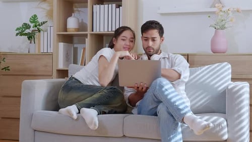 Young Couple Relaxing on Couch Using Laptop